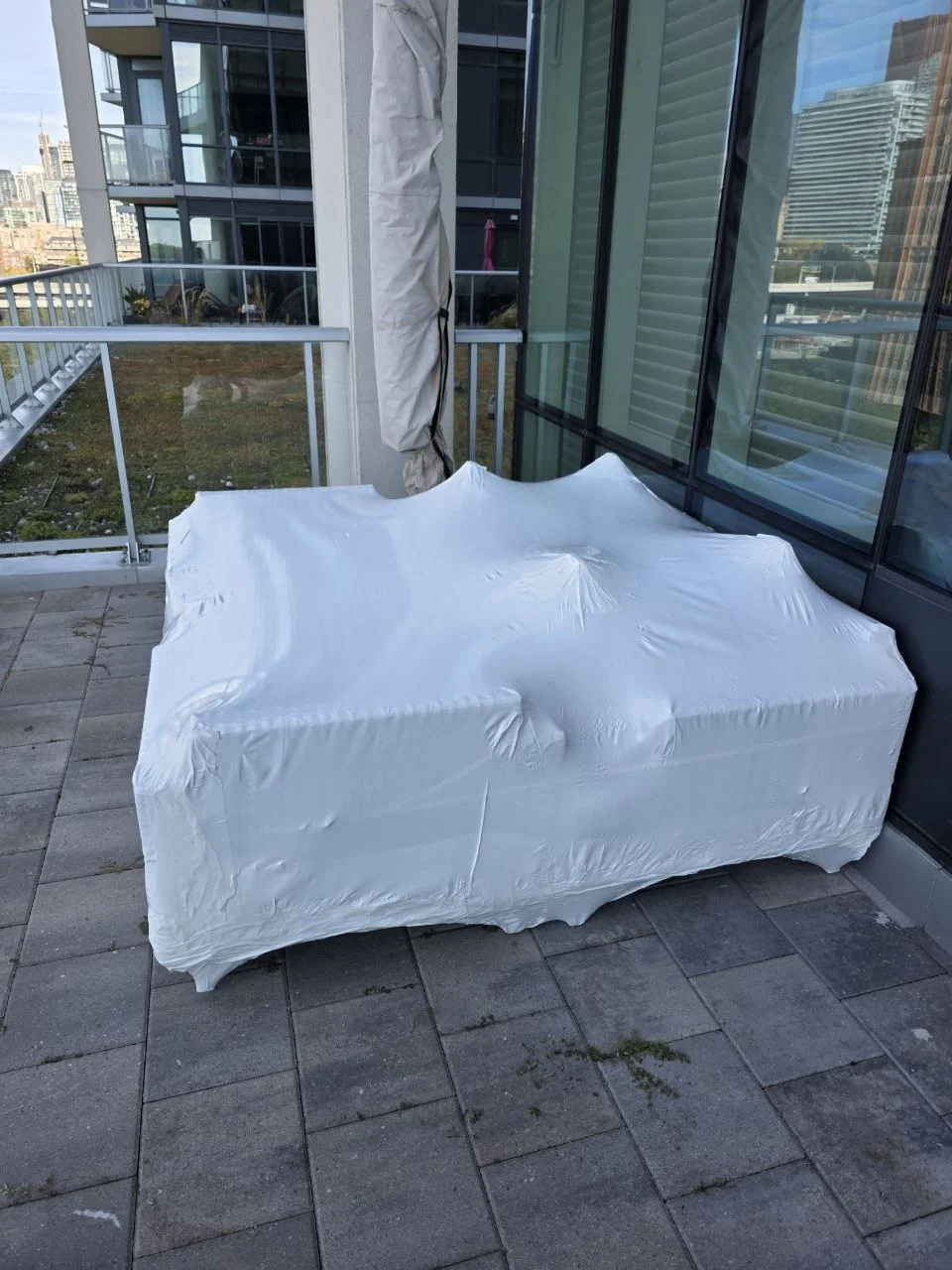 Patio furniture protected with shrink wrap on a city balcony