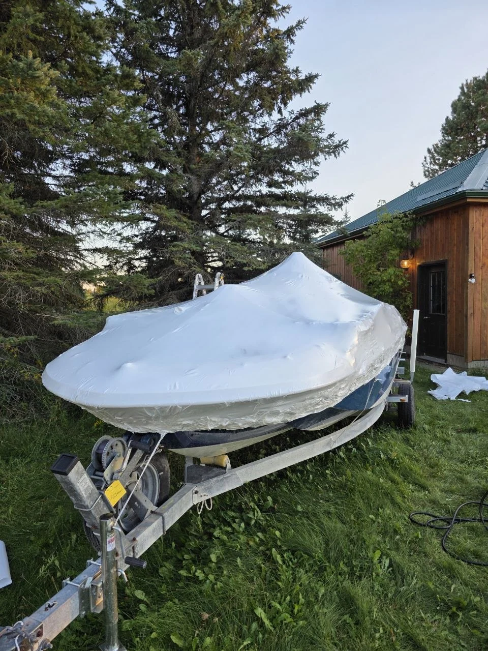 Boat protected with white shrink wrap on a trailer