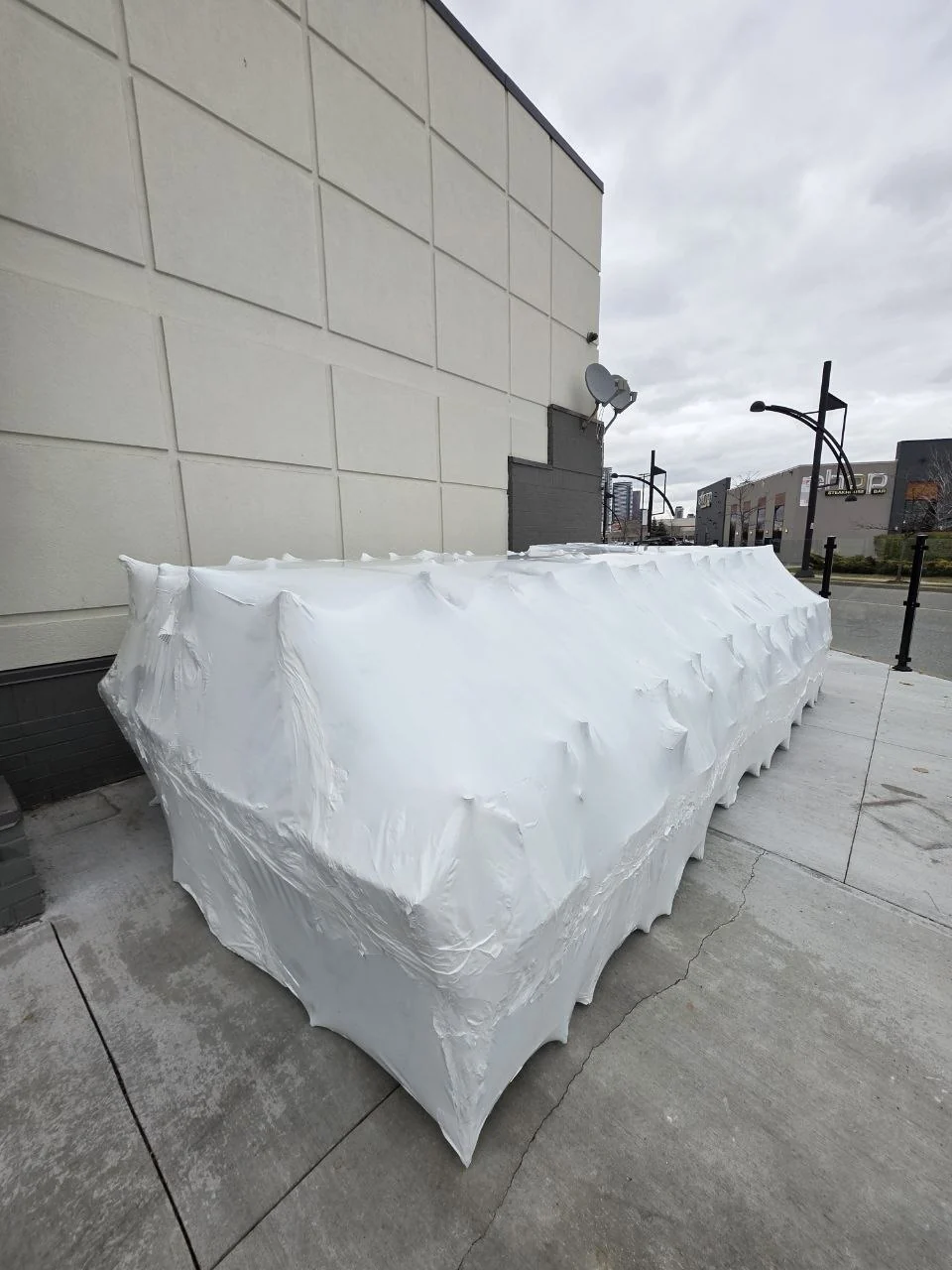 Long commercial furniture grouping sealed in white shrink wrap