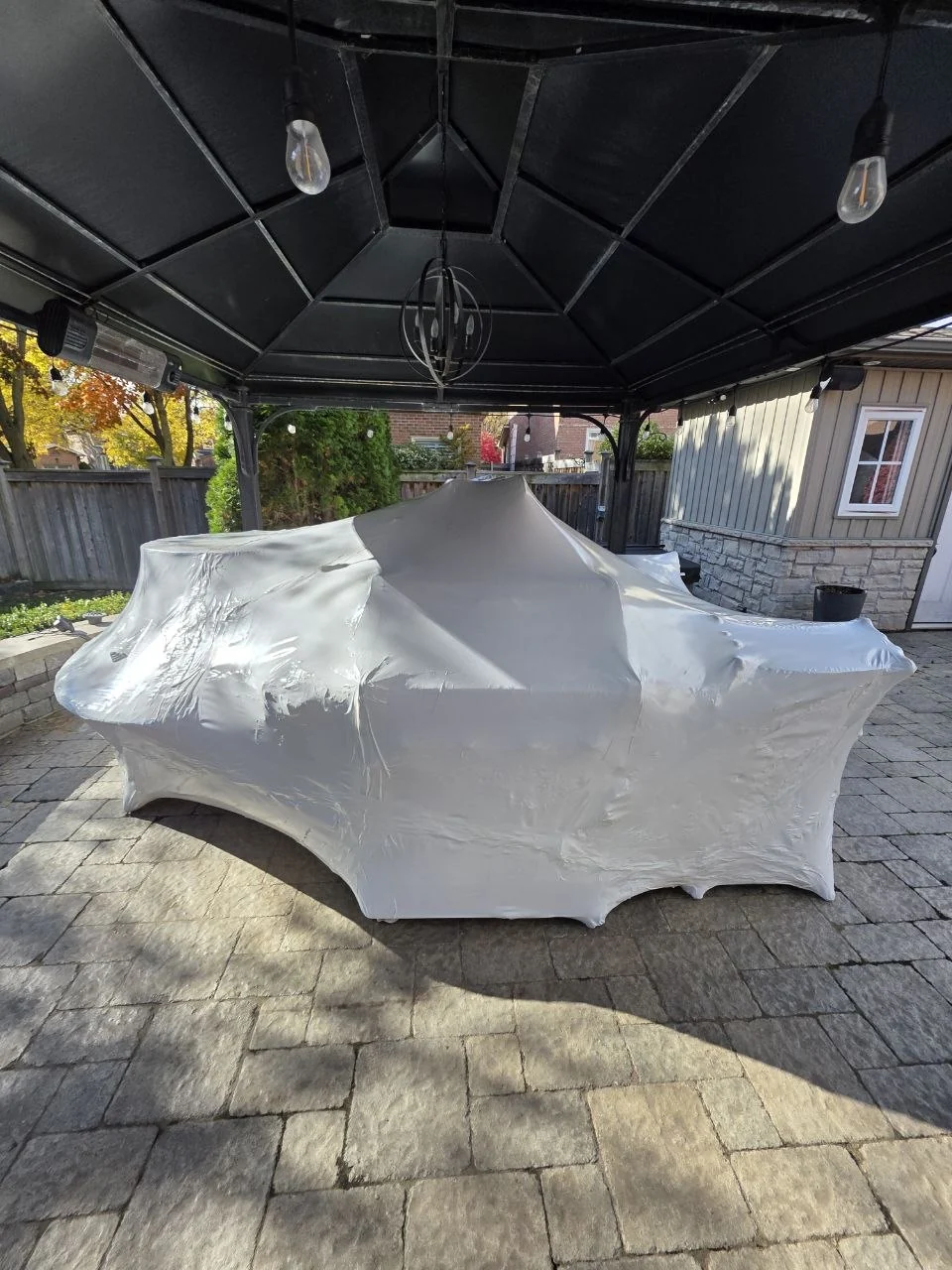Patio furniture protected with shrink wrap beneath a gazebo