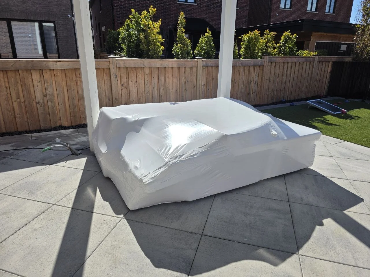 Low outdoor patio furniture grouped under white shrink wrap