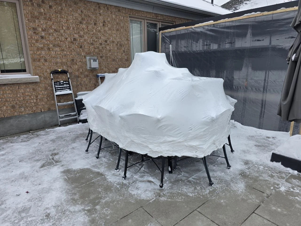 Outdoor dining set protected with shrink wrap in snow