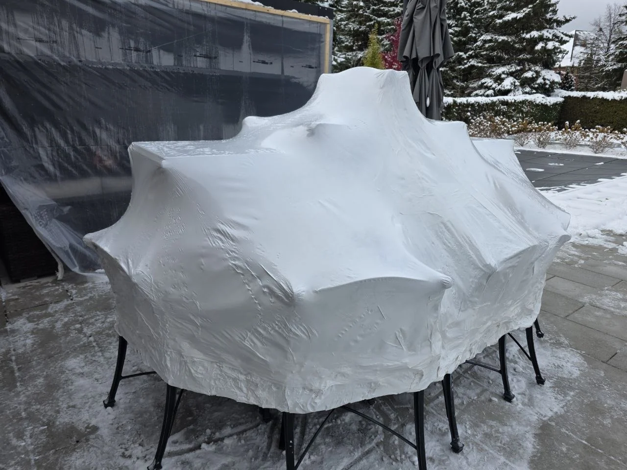 Patio furniture protected by shrink wrap in winter